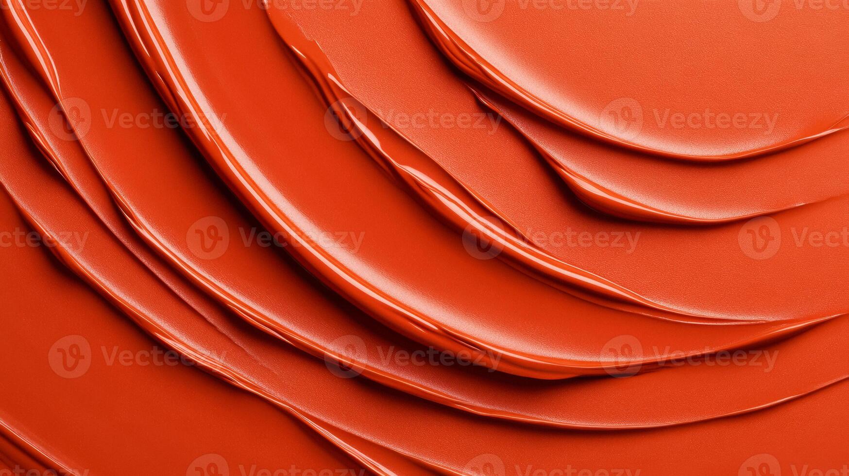 Swirls of rich coppery red liquid lipstick creating an abstract pattern on a soft muted orange background photo