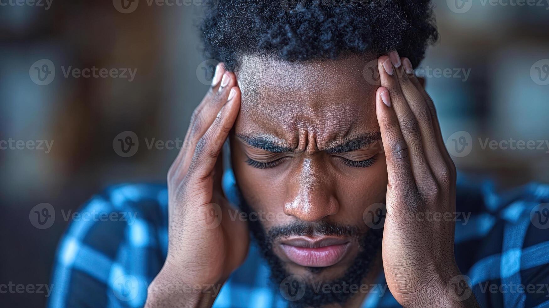 The young man is holding his head, showing signs of distress from a headache in a relaxed indoor setting photo