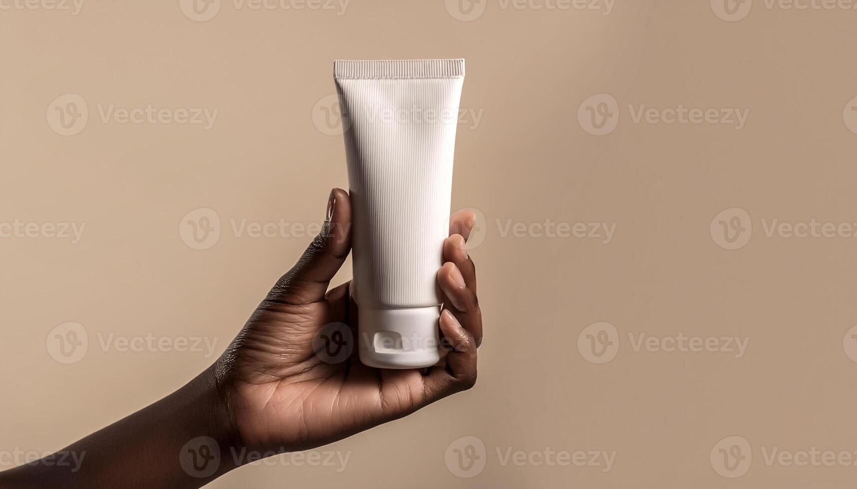 Fragile female hand holding blank mockup tube for cream or lotion on beige isolated background photo