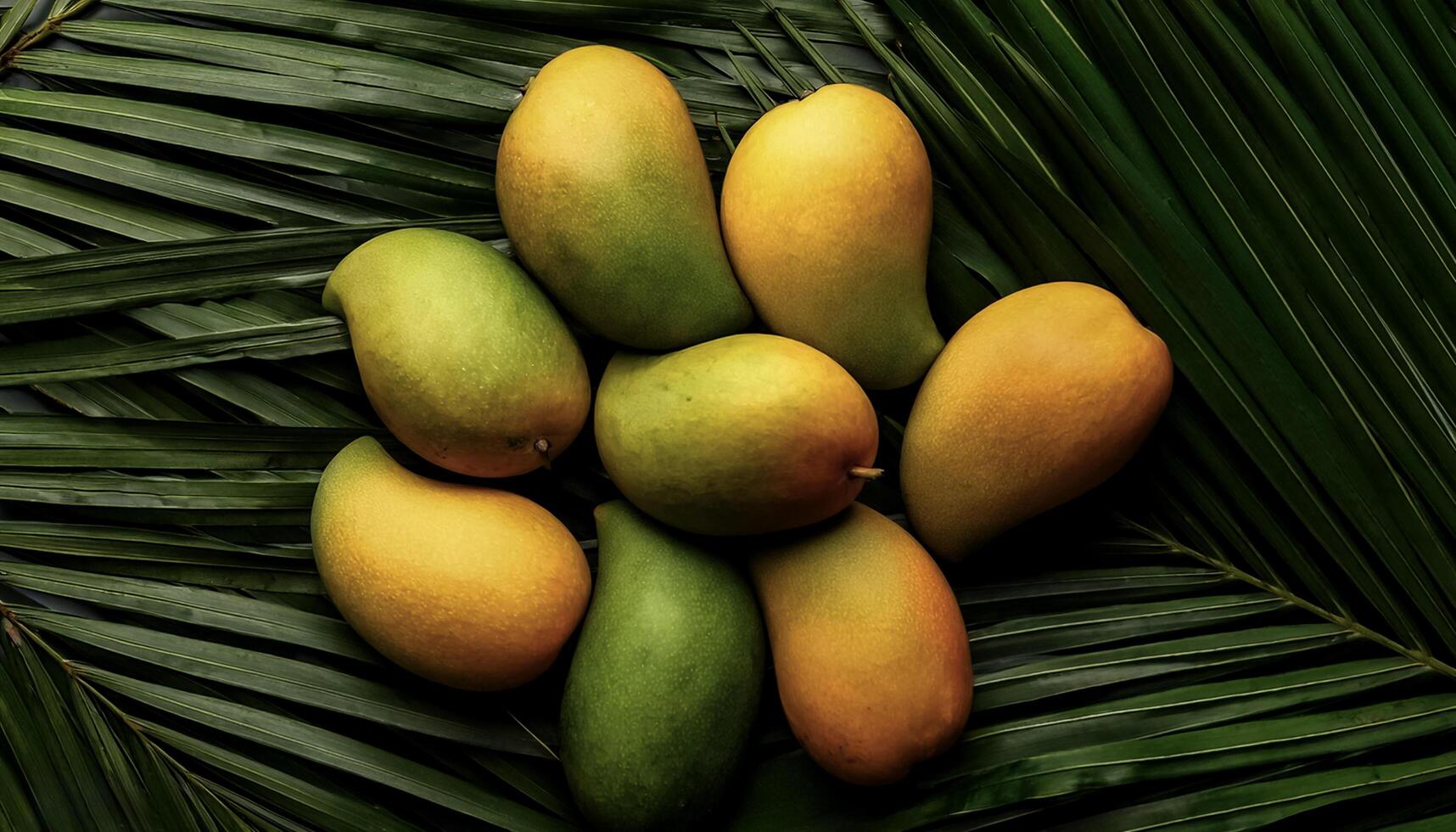 Ripe and juicy sweet mango fruits. Ripe food on the background of stacked palm leaves summer concept photo