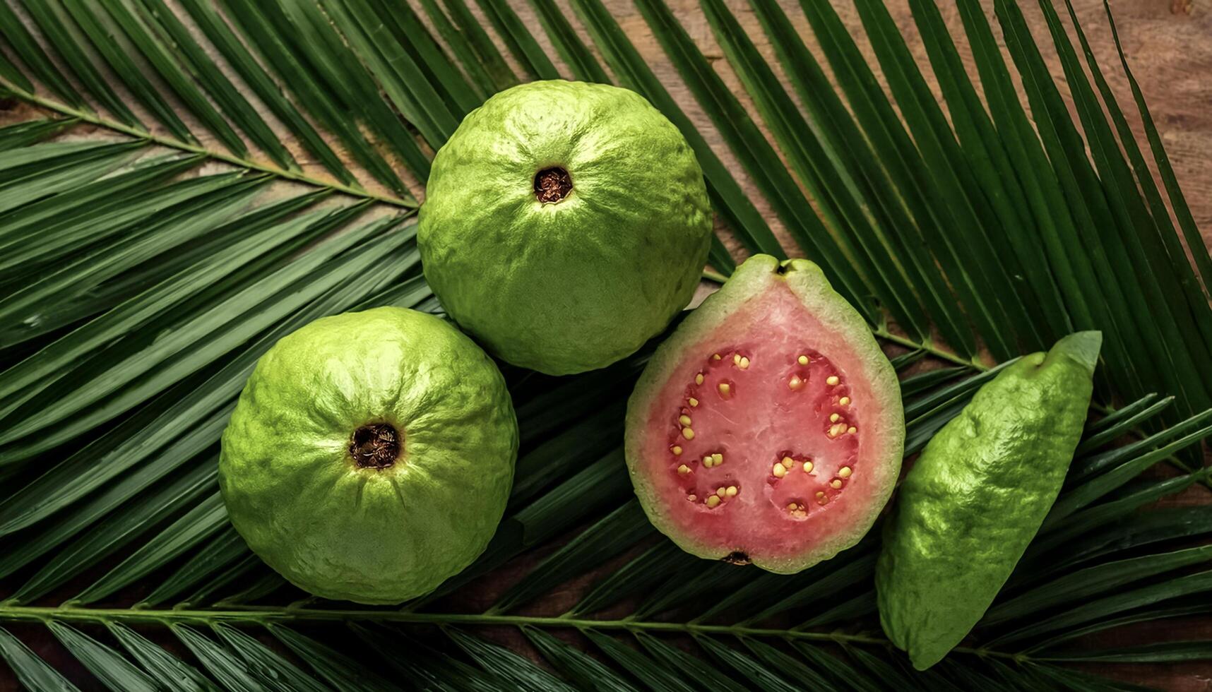 Ripe and juicy sweet Guava fruits. Ripe food on the background of stacked palm leaves summer concept photo