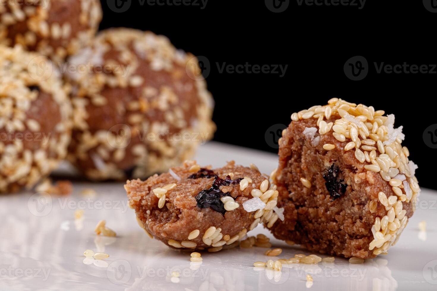 Beautiful candies with sesame seeds on a white plate on a black background photo