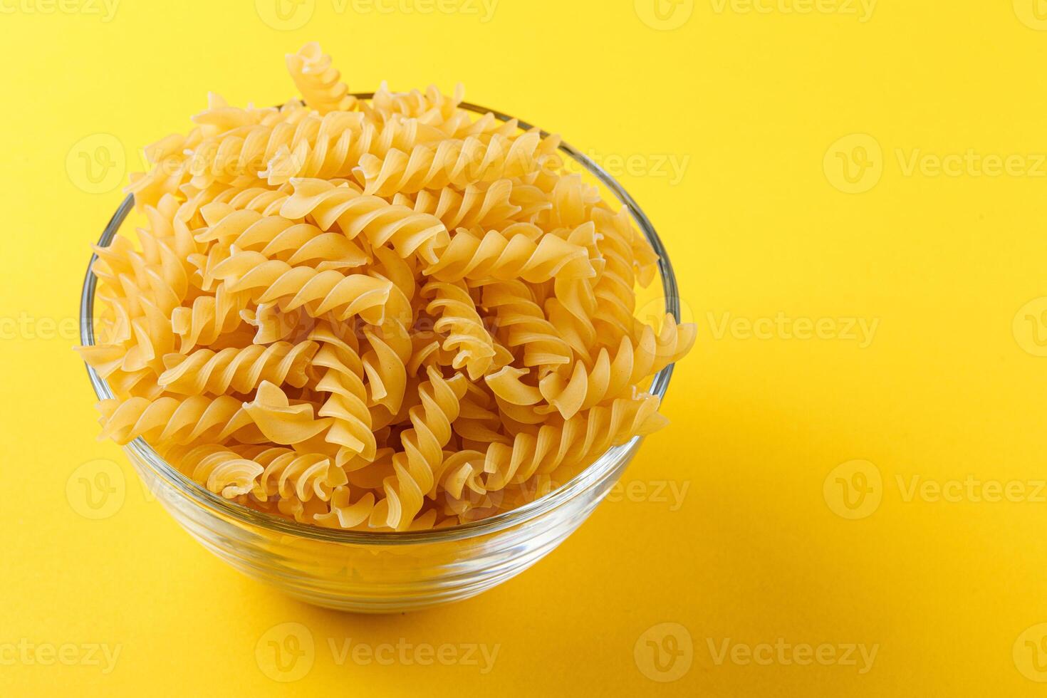 Different types and shapes of dry italian pasta on a yellow background photo
