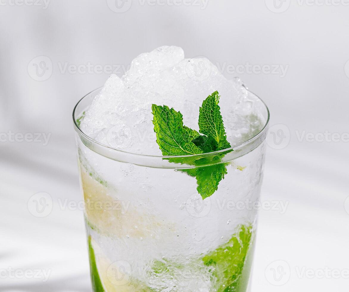 Refreshing mojito cocktail standing on white cube with tropical palm leaf shadow photo