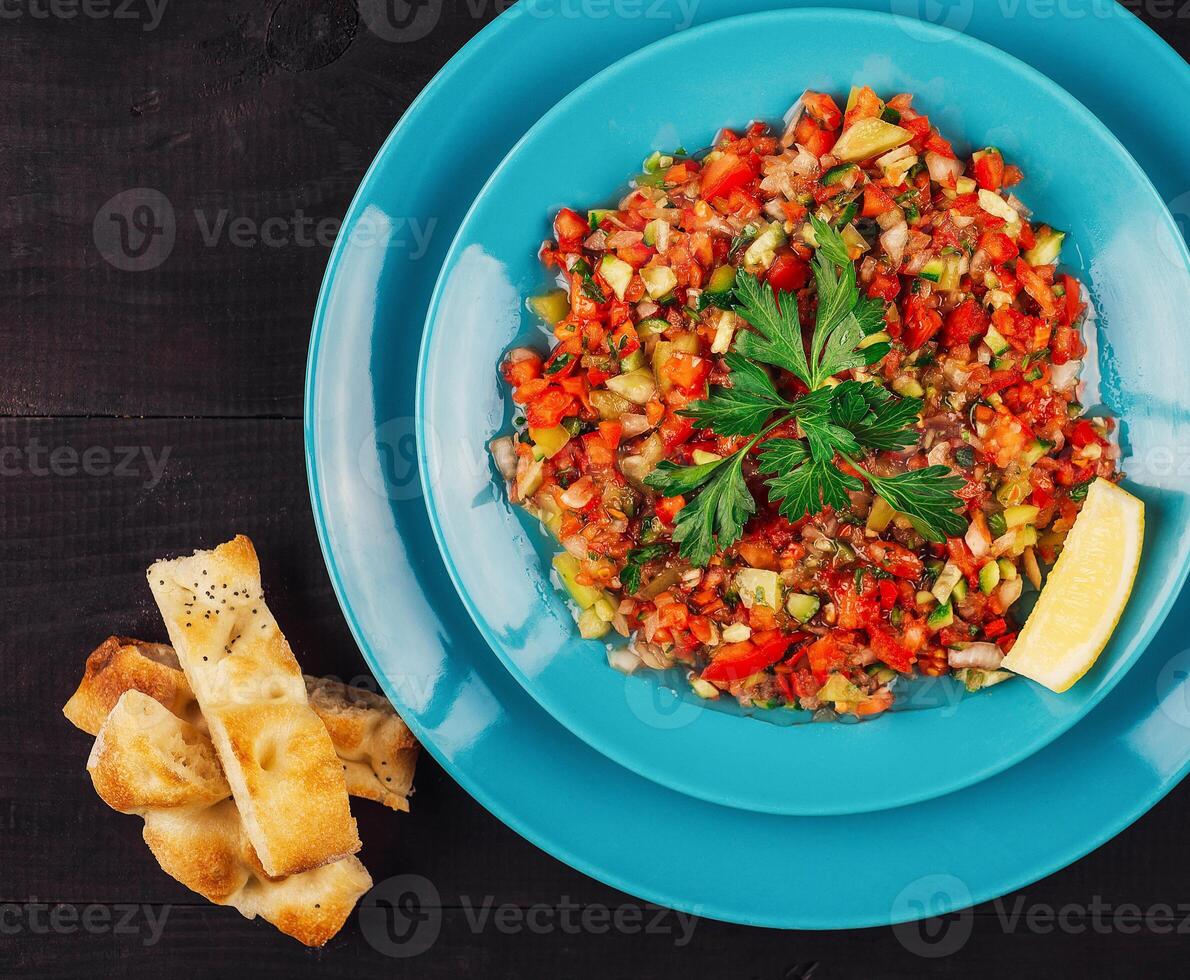 Turkish coban salad with lemon and pita bread on turquoise plate photo