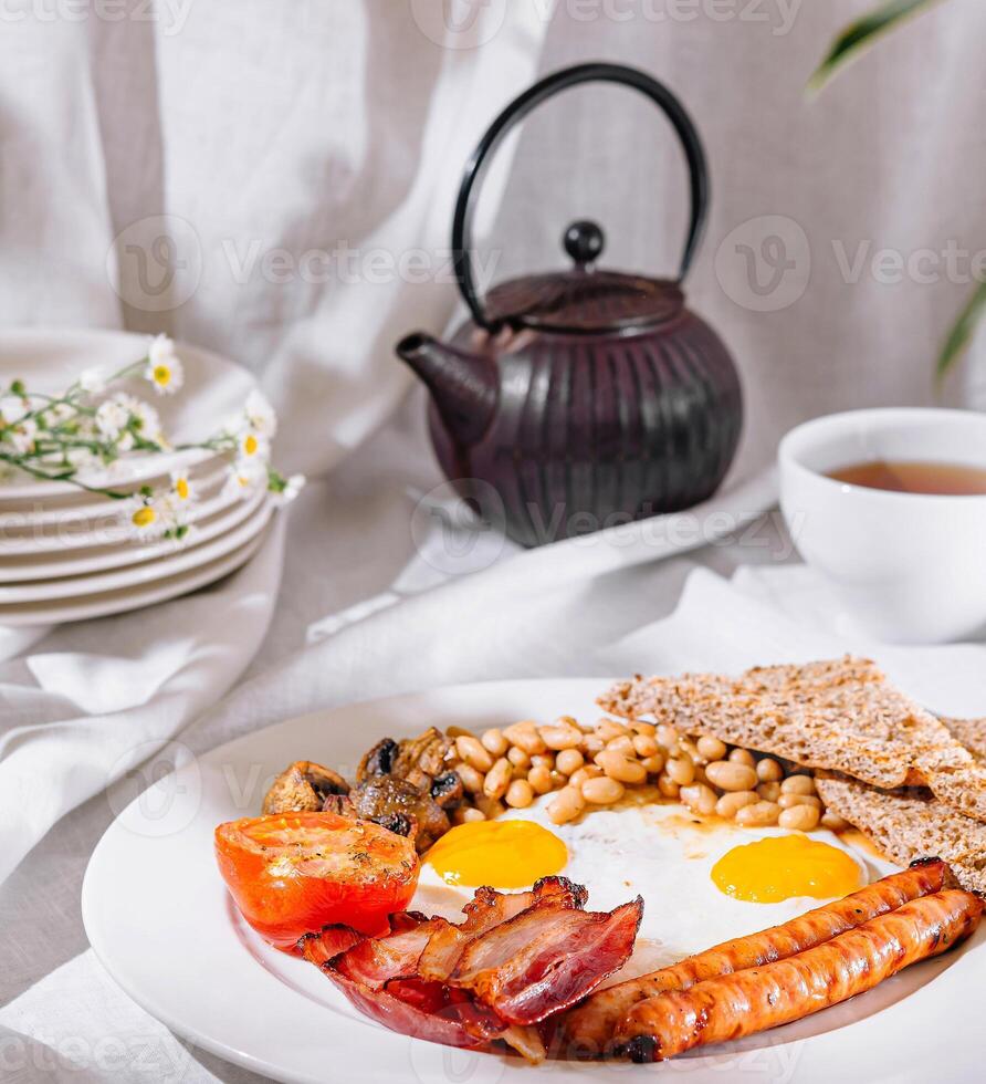 Full english breakfast with crispy bacon and sunny side up eggs being served for breakfast photo