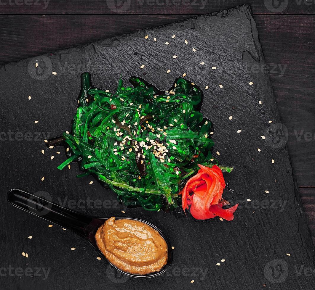 Chuka seaweed salad with nuts sauce and sesame seeds on black stone plate photo