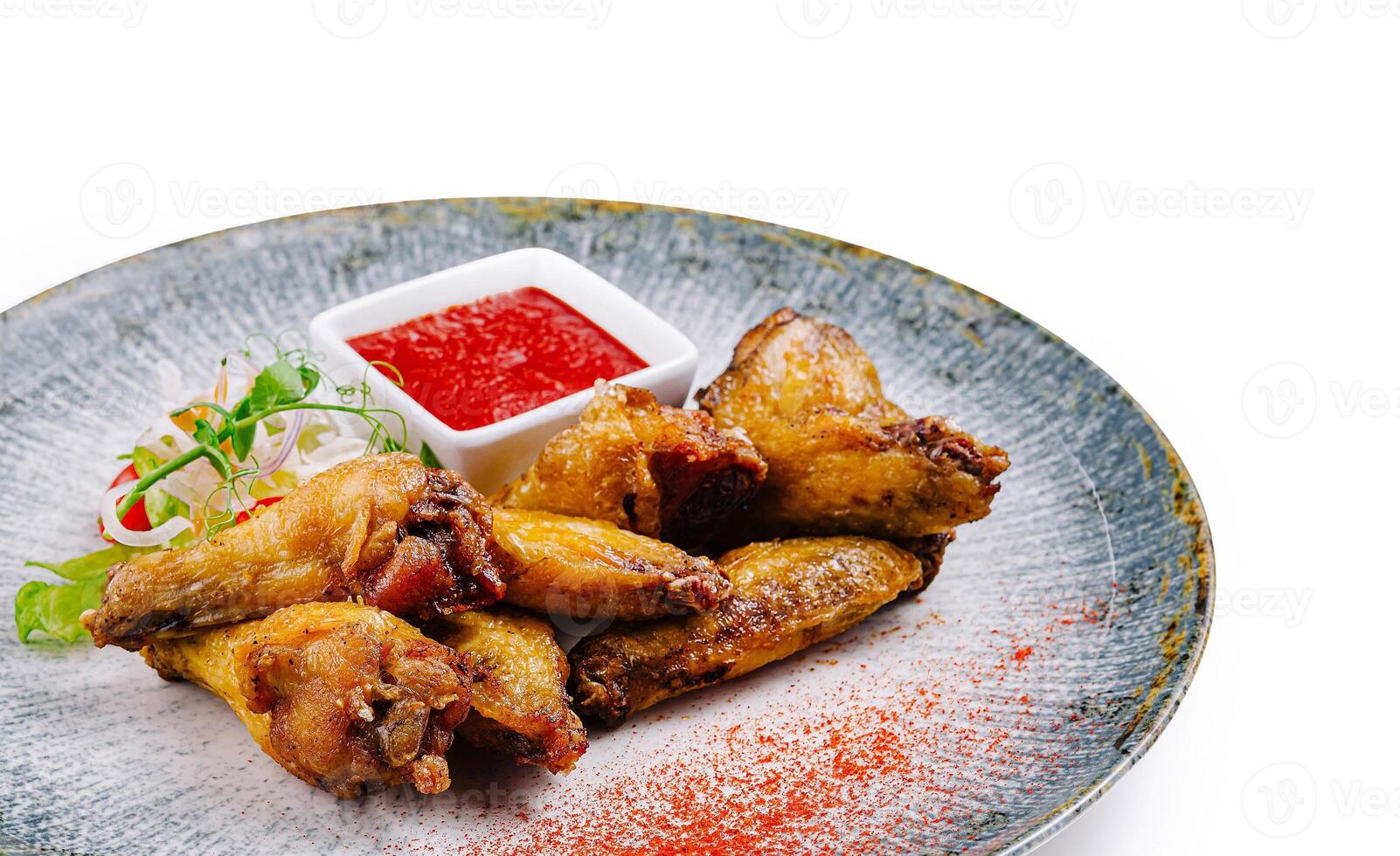 Crispy chicken wings served on modern plate with dipping sauce and garnish photo
