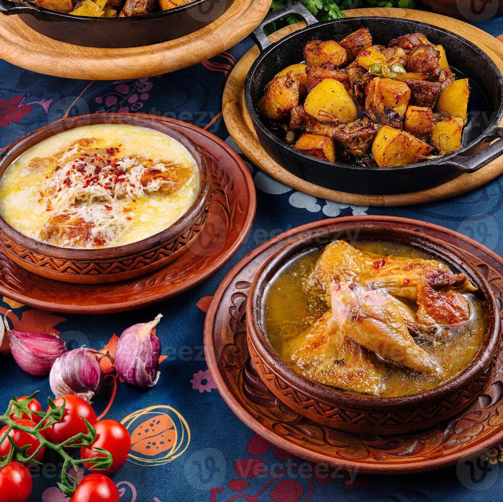 Traditional georgian food served in clay pots standing on a decorated table photo