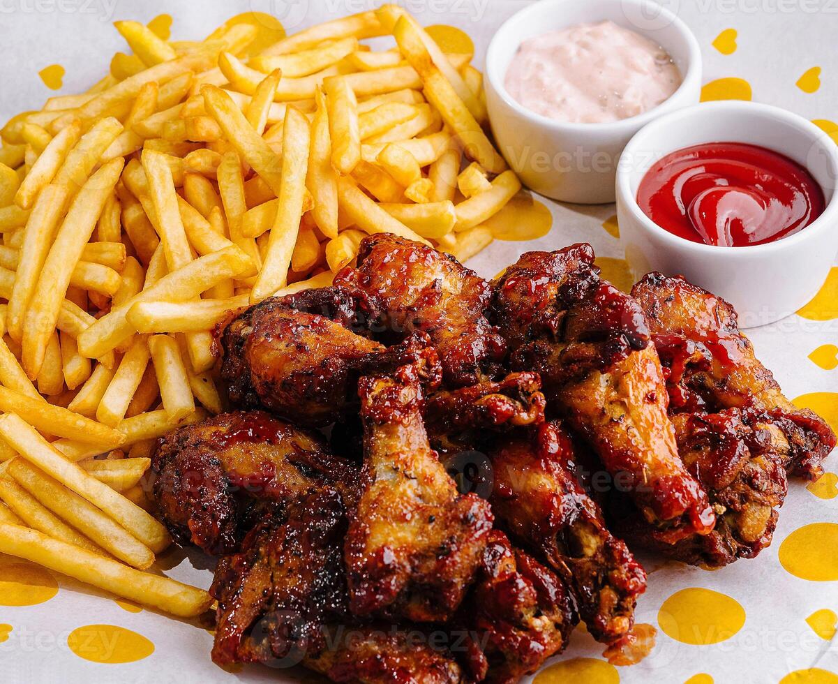 Crispy chicken wings and fries with dips on table photo