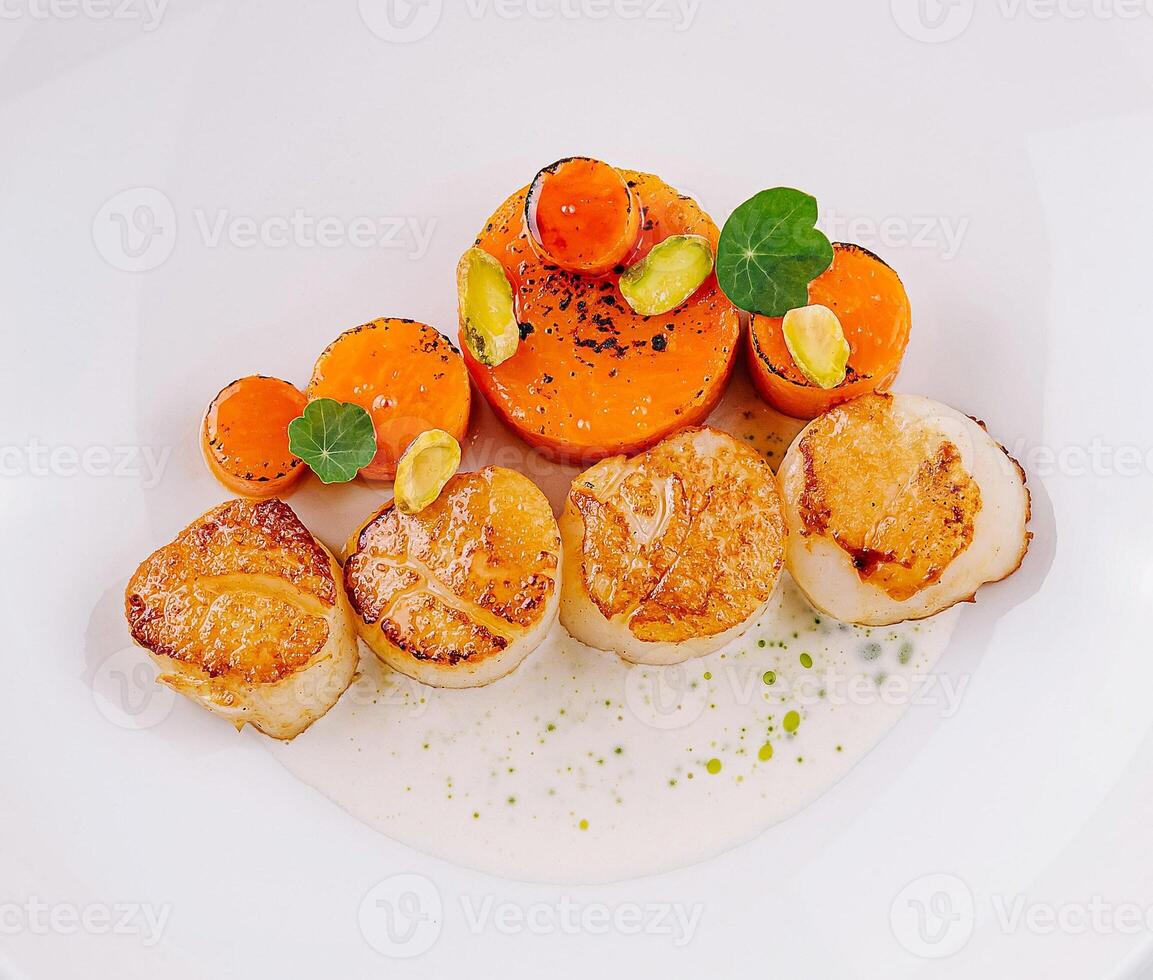 Delicious fried scallops served on white plate with creamy sauce and vegetables photo