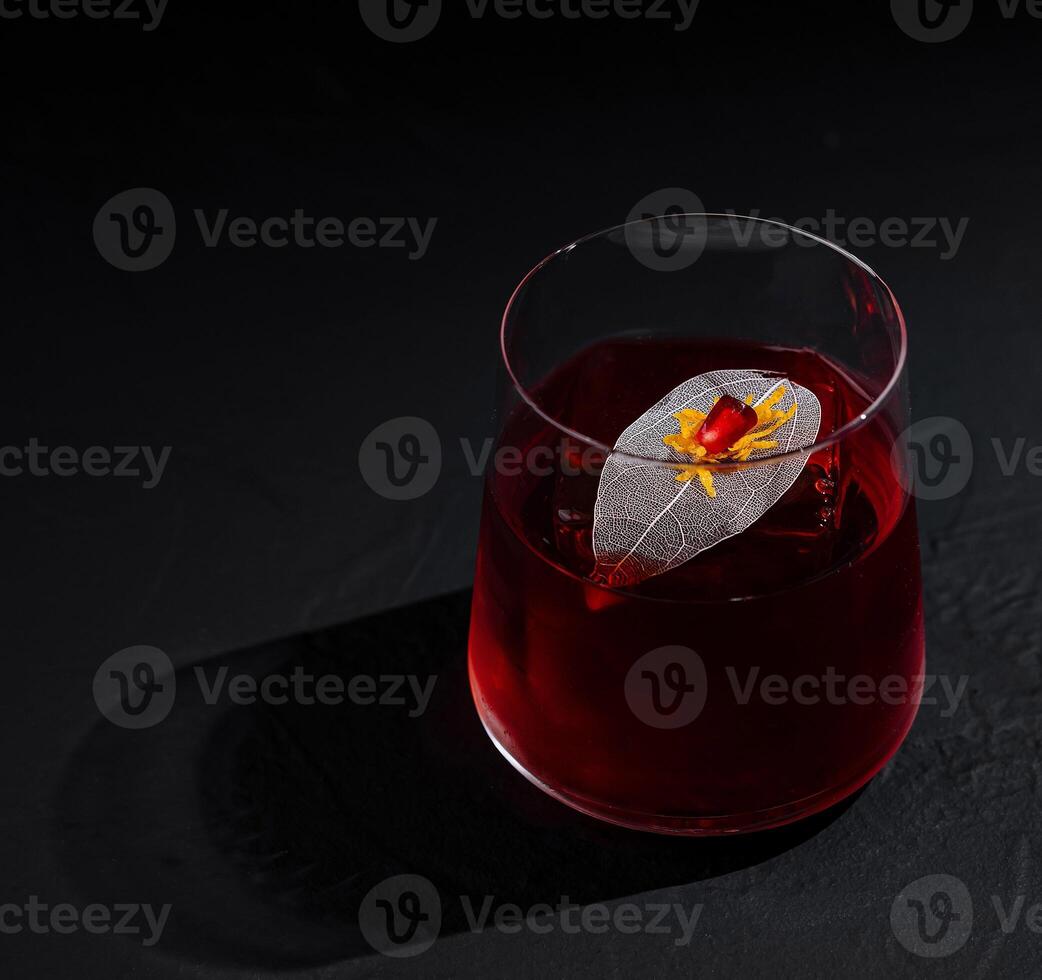 Elegant cocktail with floral garnish on dark background photo