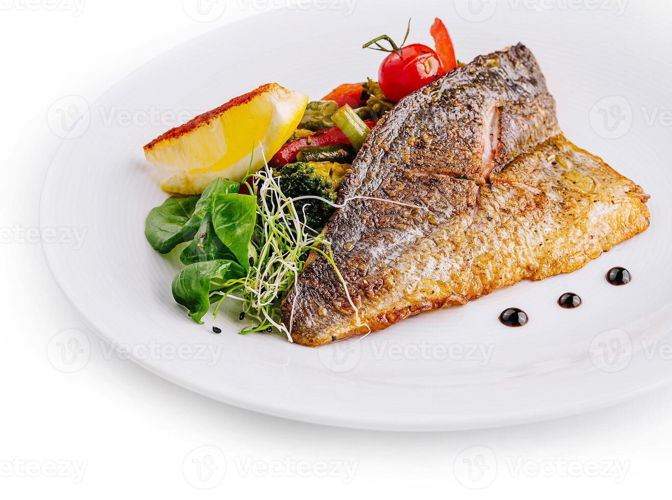 Delicious grilled fish with vegetables and lemon on white plate photo
