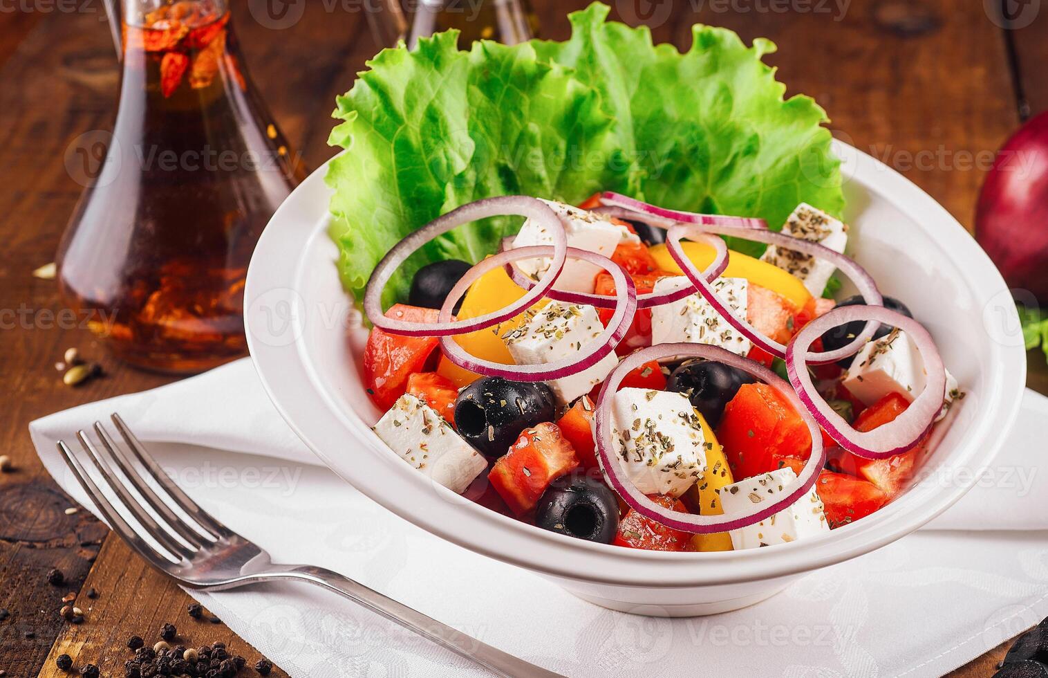 Greek salad with feta cheese, vegetables and olives on rustic wooden table background photo
