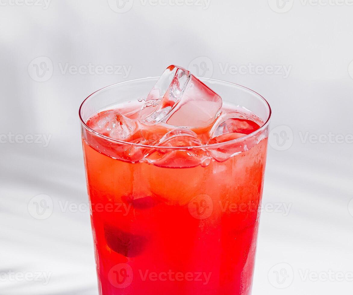 Red cocktail standing on white cube with palm leaf shadow photo