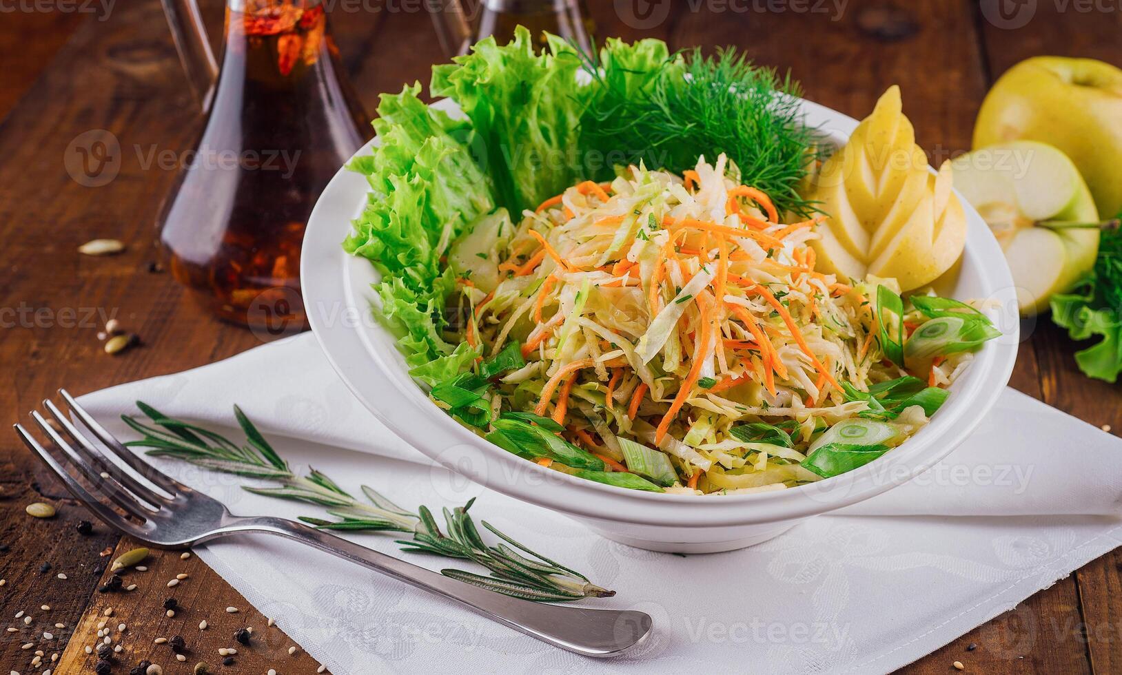 Fresh cabbage salad with apple slices and herbs on wooden table photo