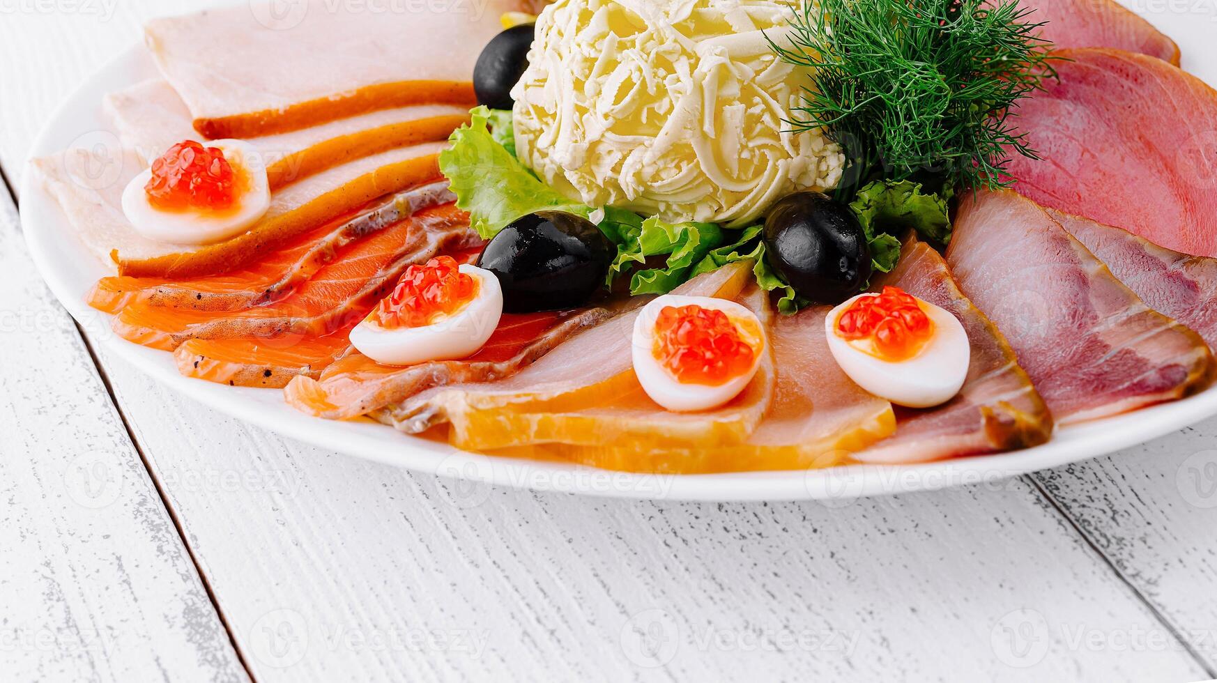 Delicious sliced fish platter with butter lemon and olives on white table photo