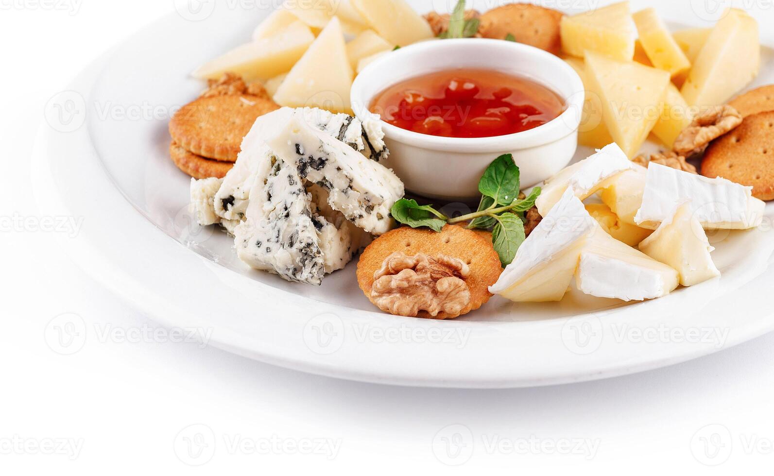 Delicious cheese plate presenting variety of cheeses, nuts, and sauce photo