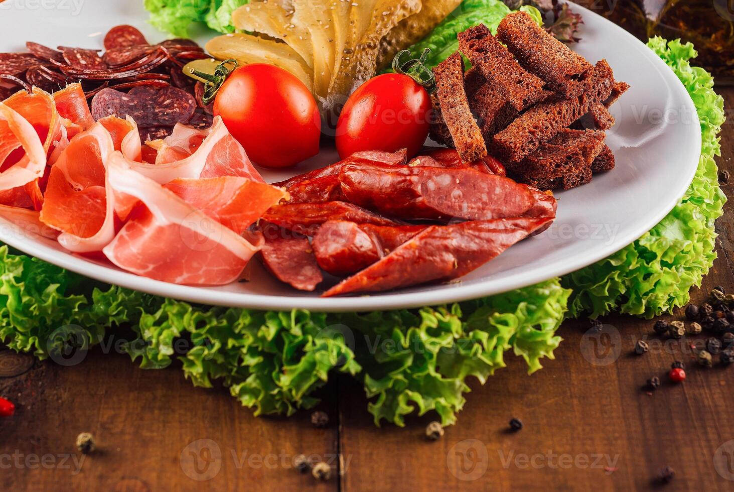Delicious meat platter with various smoked meats and pickles on wooden table photo