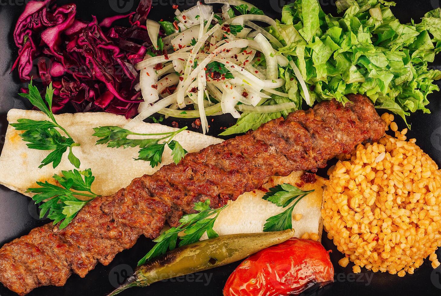 Traditional turkish adana kebab serving with vegetables and bulgur rice pilaf photo