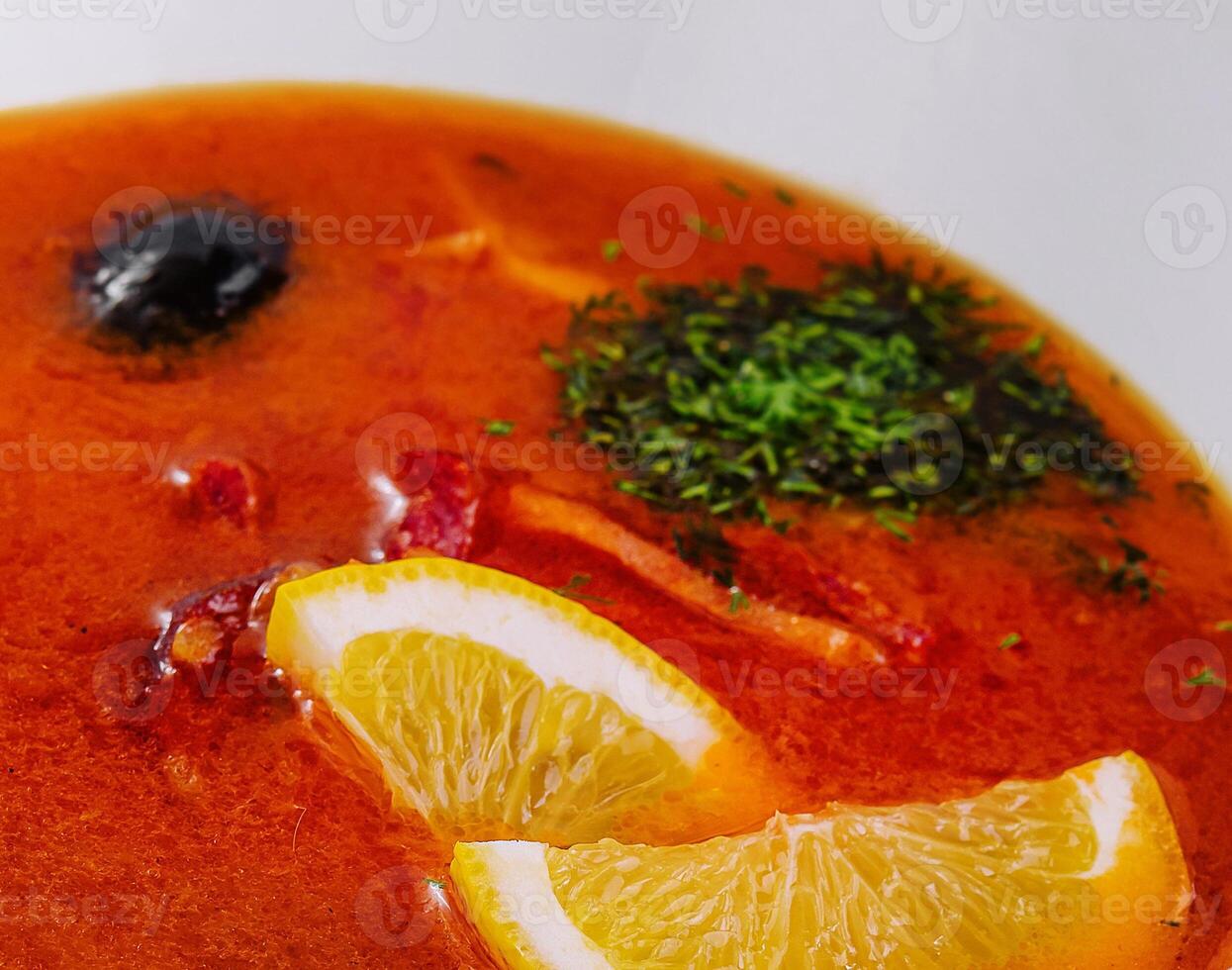 Rich tomato soup with lemon and herbs close-up photo