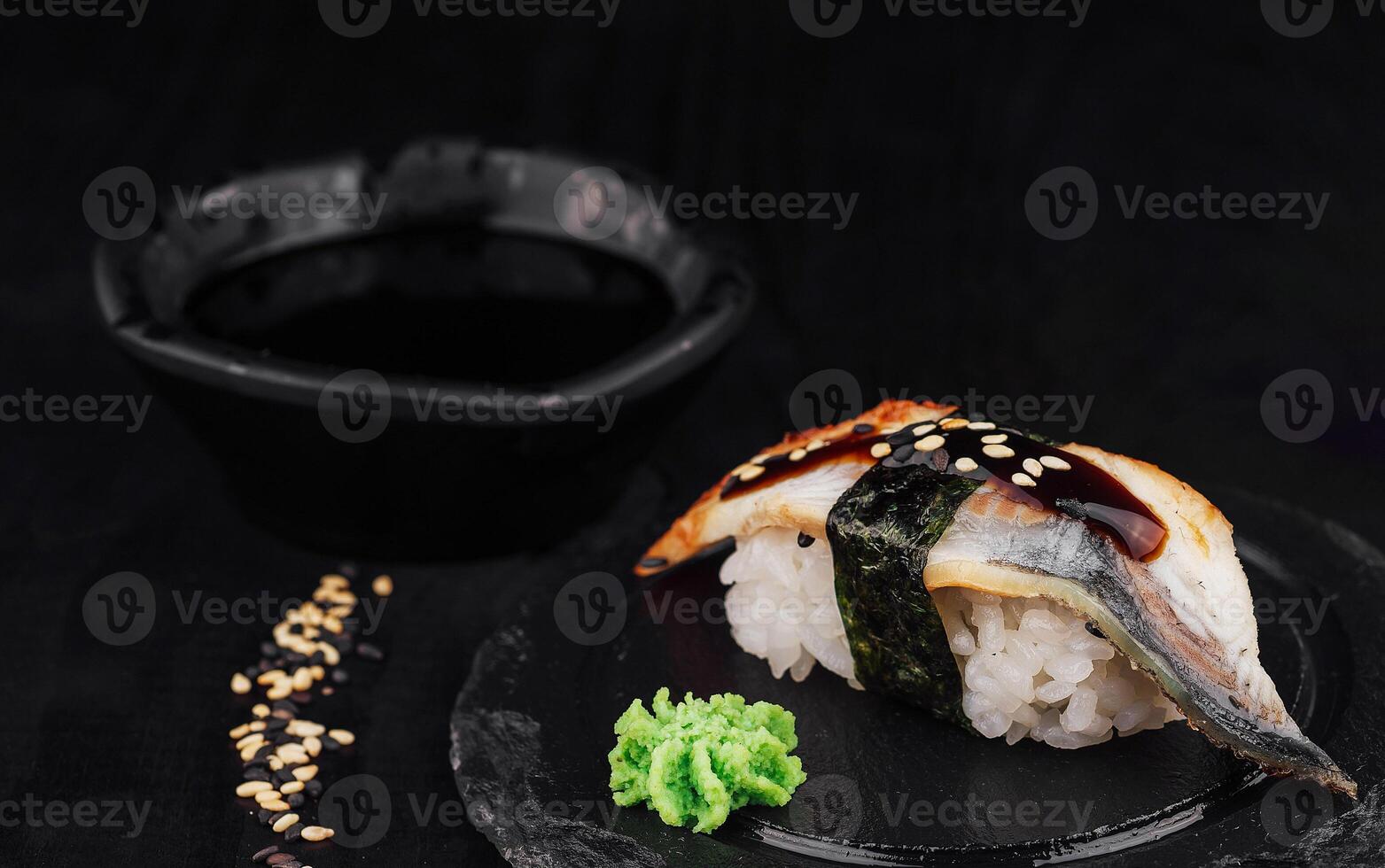 Delicious unagi nigiri sushi with ginger and soy sauce on black background photo