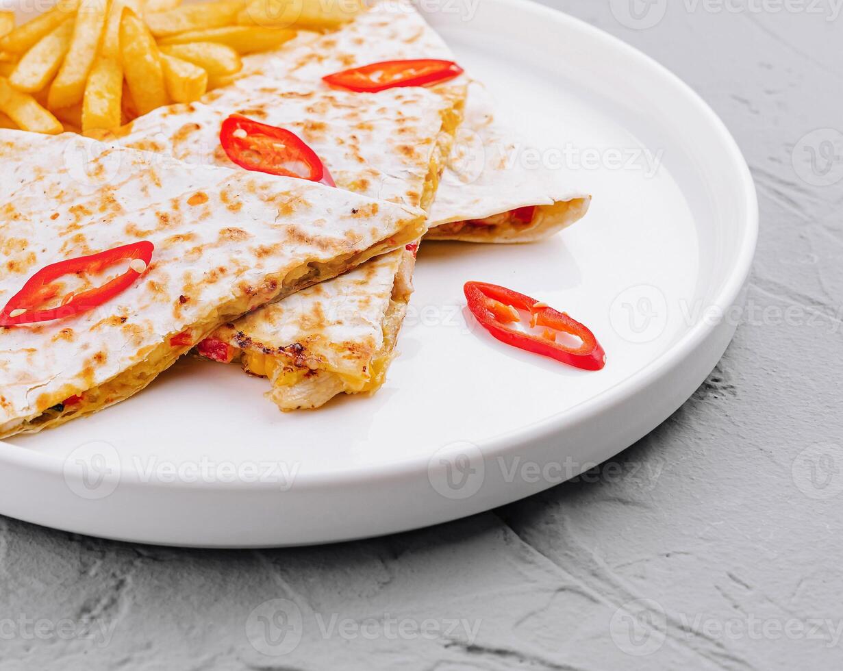 Spicy chicken quesadilla with french fries on plate photo