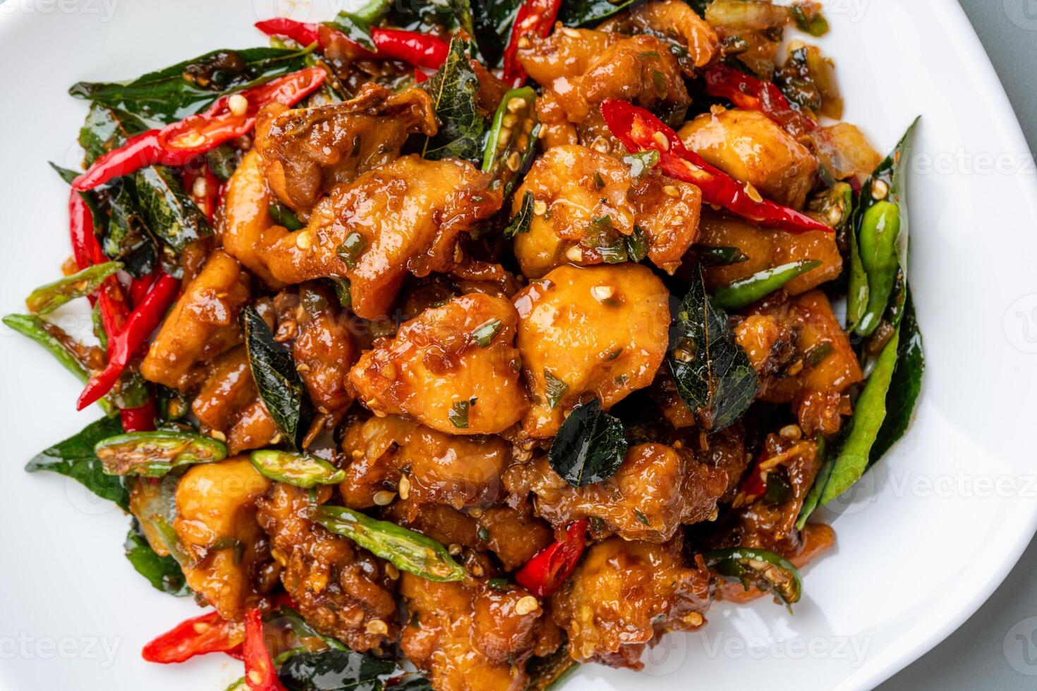 Ayam Tangkap, spices fried chicken original from Aceh, Indonesia. served with leaves such as temurui or curry leaves, pandan leaves and green chili, that are roughly chopped and fried crispy. photo