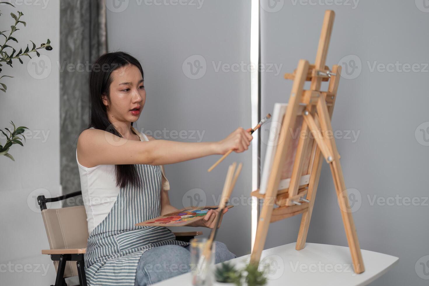Young Woman Drawing on Canvas in Modern Room, Relaxing and Creating Art in a Comfortable Home Environment photo