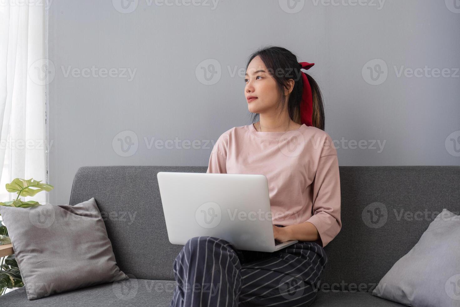 Relaxed Young Woman Using Laptop to Explore Social Media While Sitting on a Comfortable Sofa in a Modern Home Setting photo