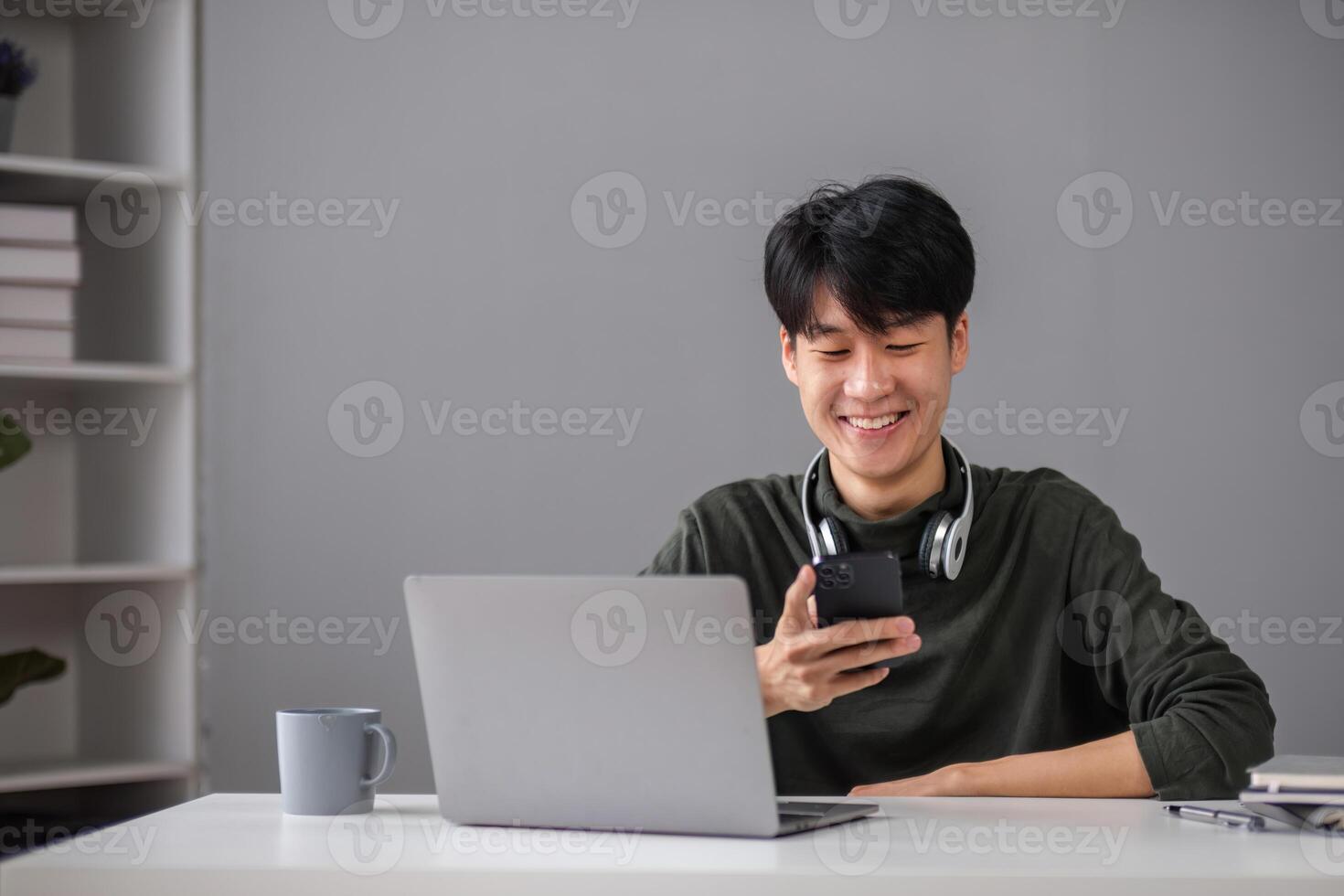 Young Boy Studying Online with Laptop and Smartphone in Modern Home Setting, Smiling and Engaged in Learning photo