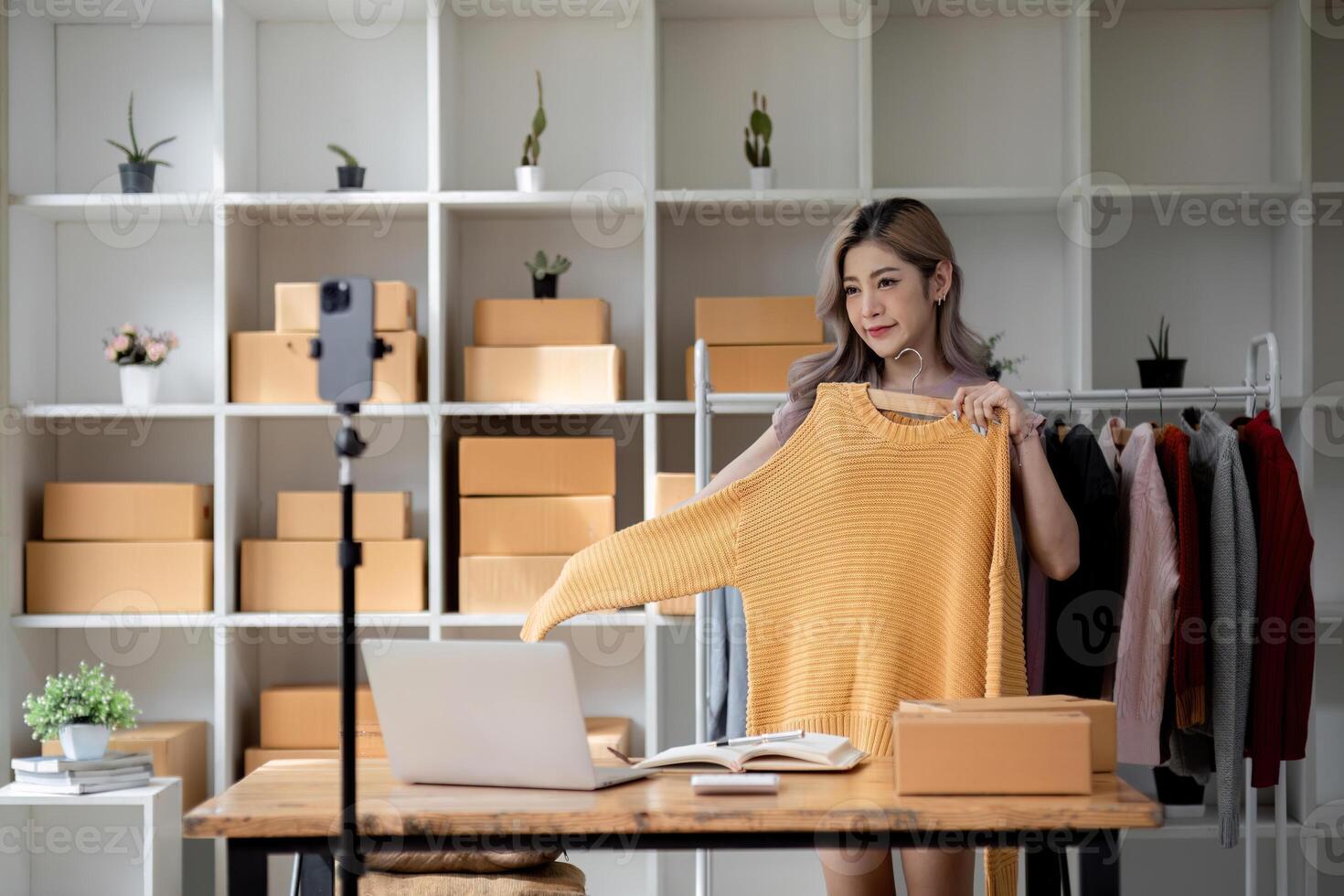 Female Business Owner Livestreaming and Selling Shirts Online from Home Office with Modern Decor photo