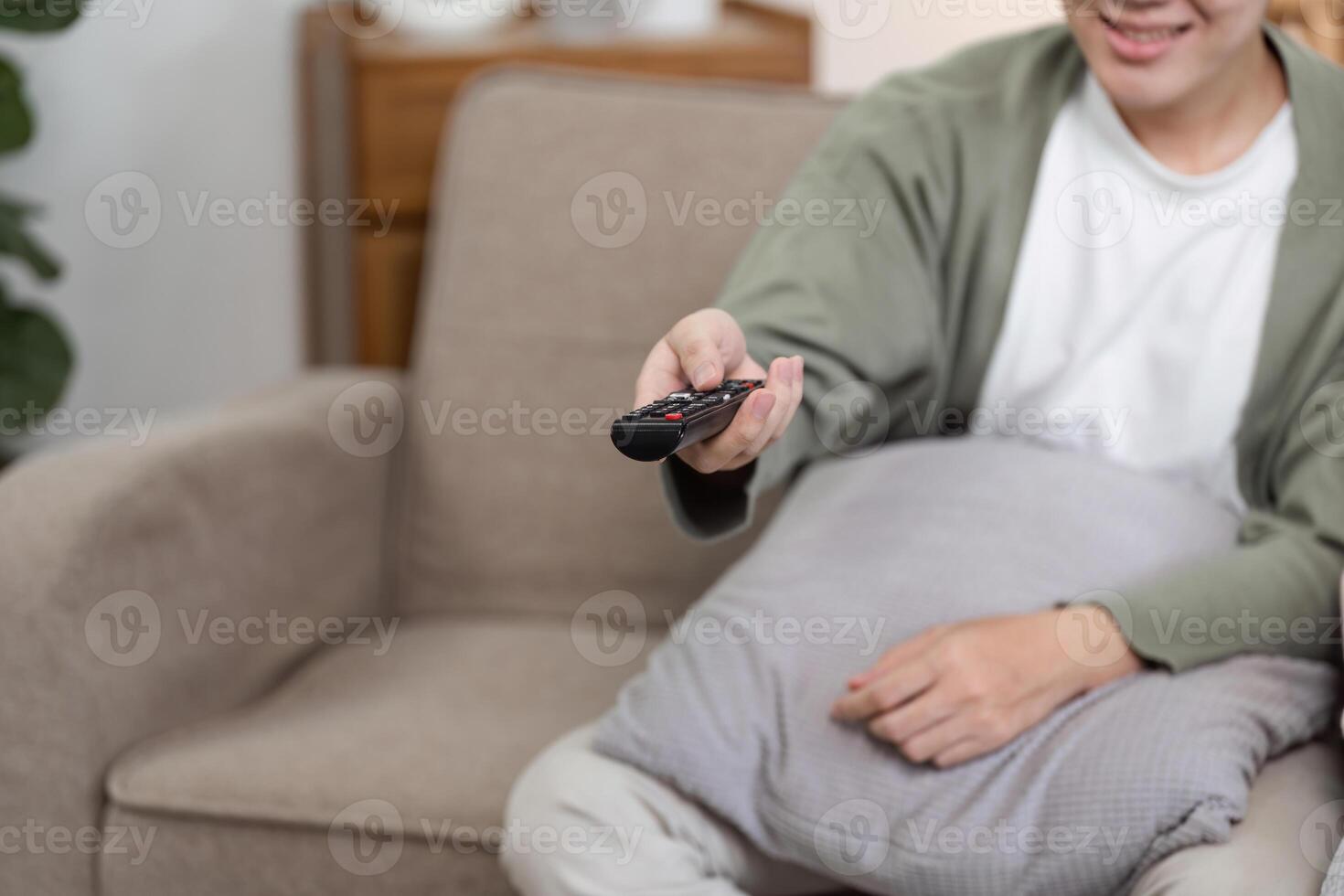 Man Relaxing on Sofa Watching TV with Remote Control in Hand in Modern Living Room Setting photo