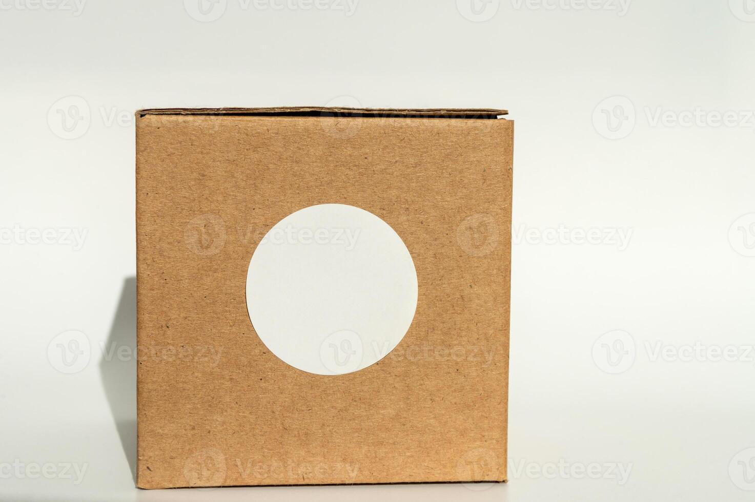 Brown cardboard box with white circular sticker on a neutral background. photo