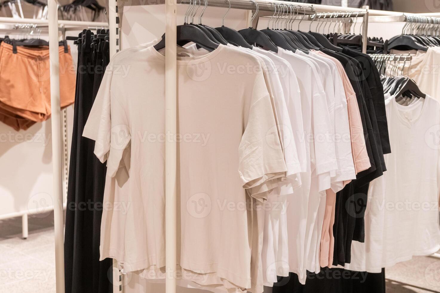 Various t-shirts in neutral colors on hangers in retail clothing store. photo