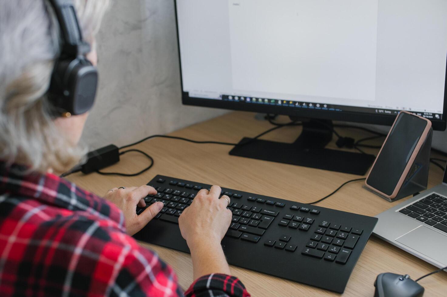Senior Woman with Headphones Using Computer at Desk photo