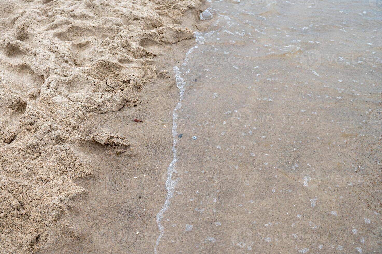 Shallow waves washing onto sandy beach shore. photo