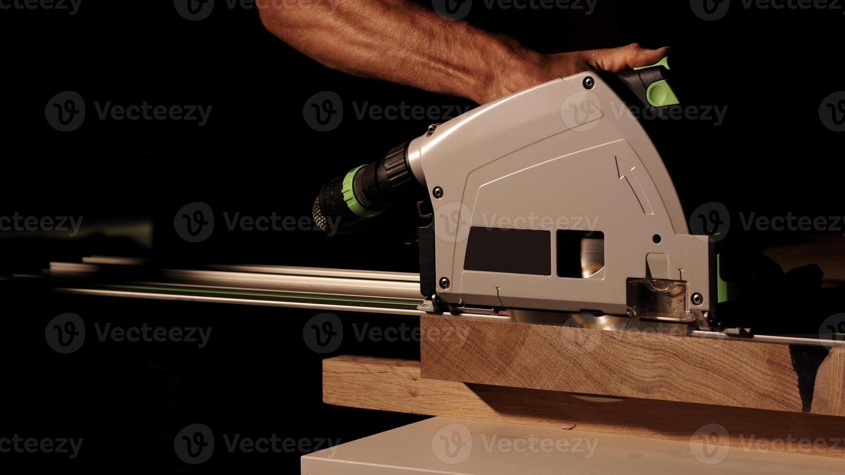 Close-up of a man cuts a wooden plank with an electric circular saw in a workshop. Cutting a piece of wood on a circular saw in backlight. Ideal topics related carpentry, efficient sawing techniques photo