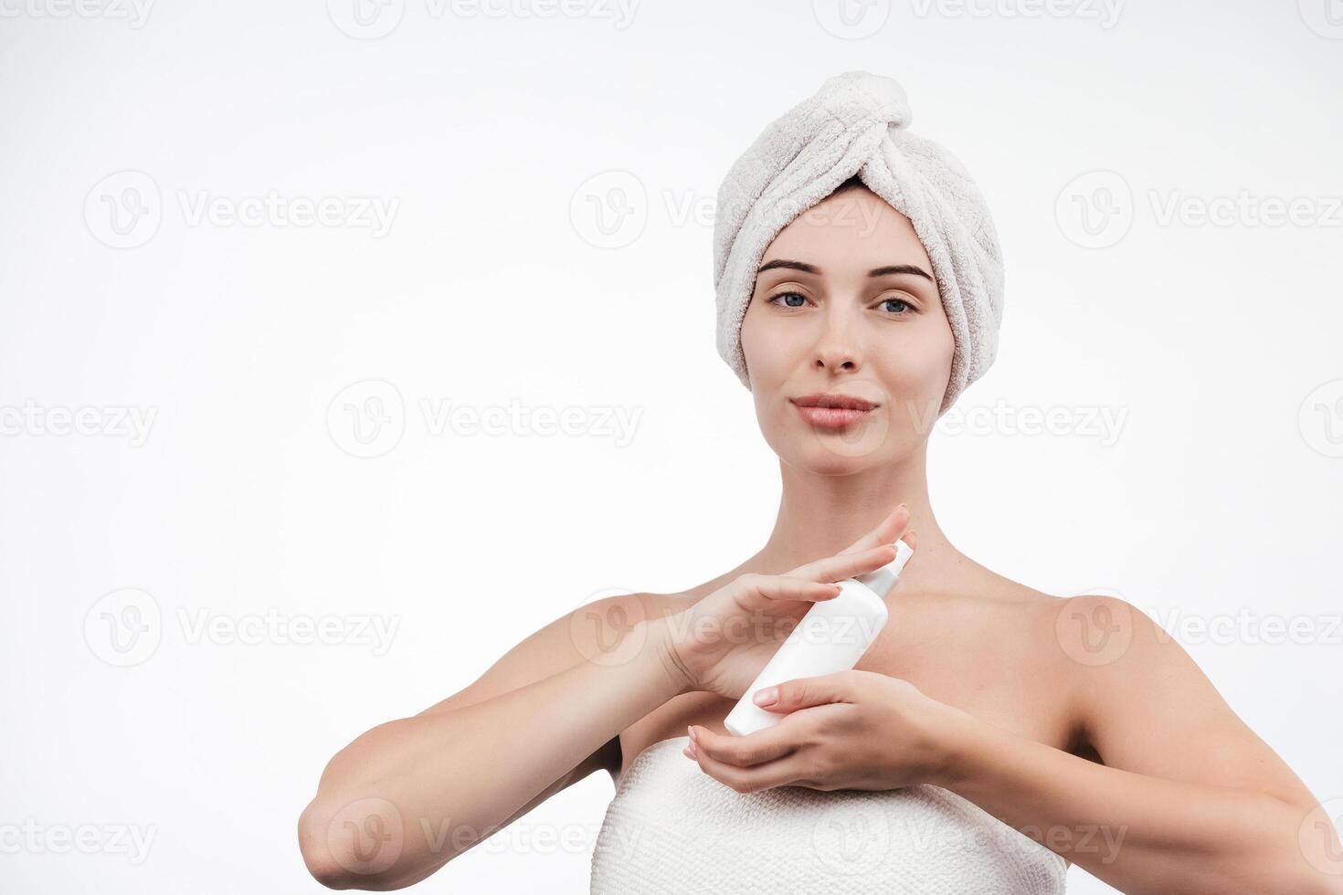A woman with flawless skin wearing a hair towel after a spa treatment. Her relaxed expression evokes a sense of harmony and self-care against a white background photo
