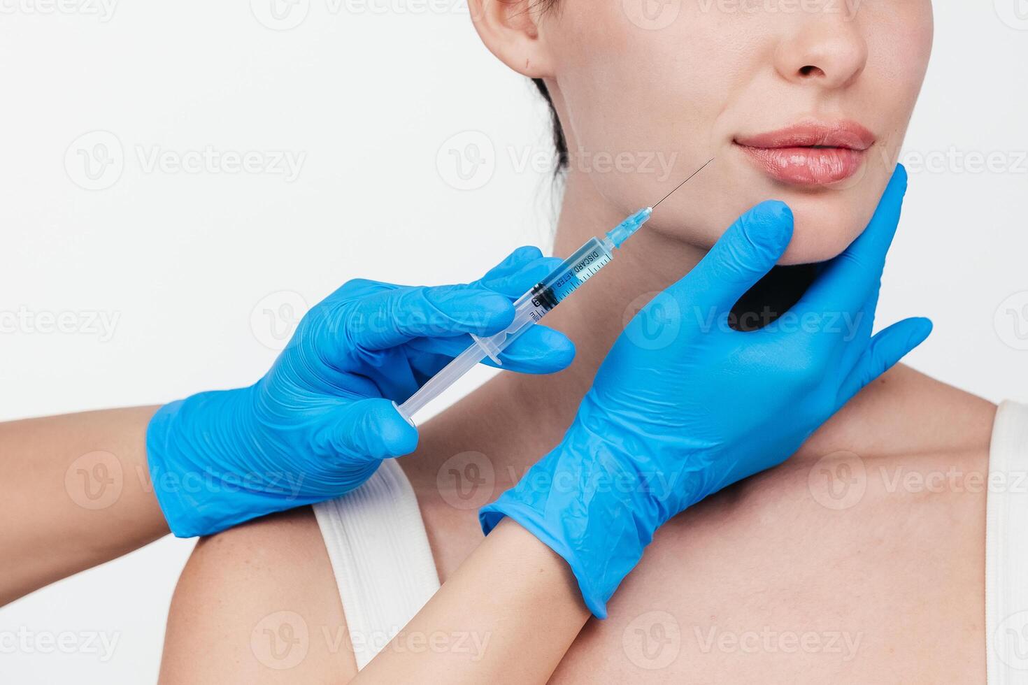 Woman while procedure lip augmentation at cosmetology clinic with beautician. Filler injection for beautiful female lips augmentation with hyaluronic, side view. photo