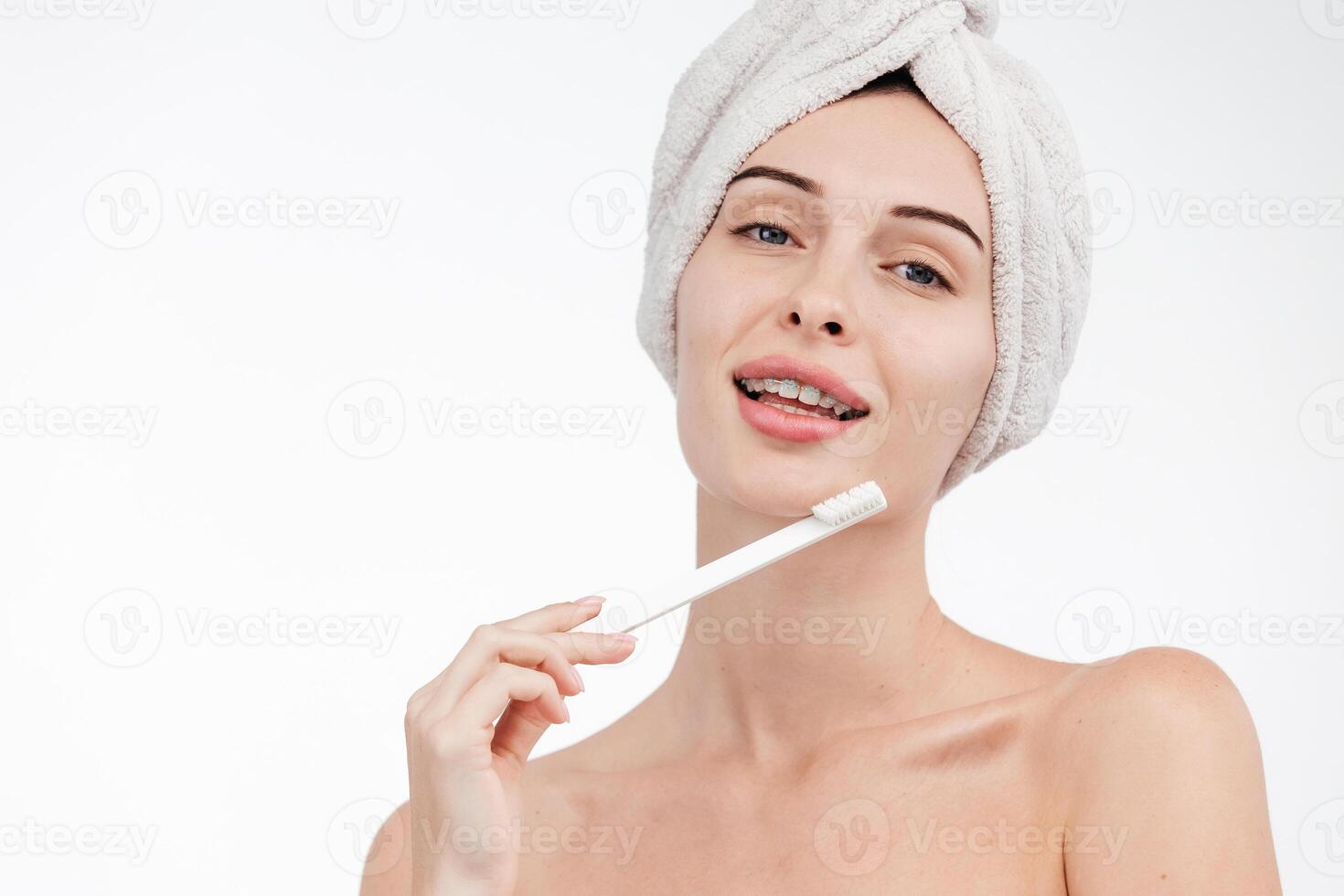 Smiling woman holding toothbrush with braces on teeth isolated on white background, Concept oral hygiene and health care. Orthodontic concept. Invisible braces aligner, recommending this new treatment photo