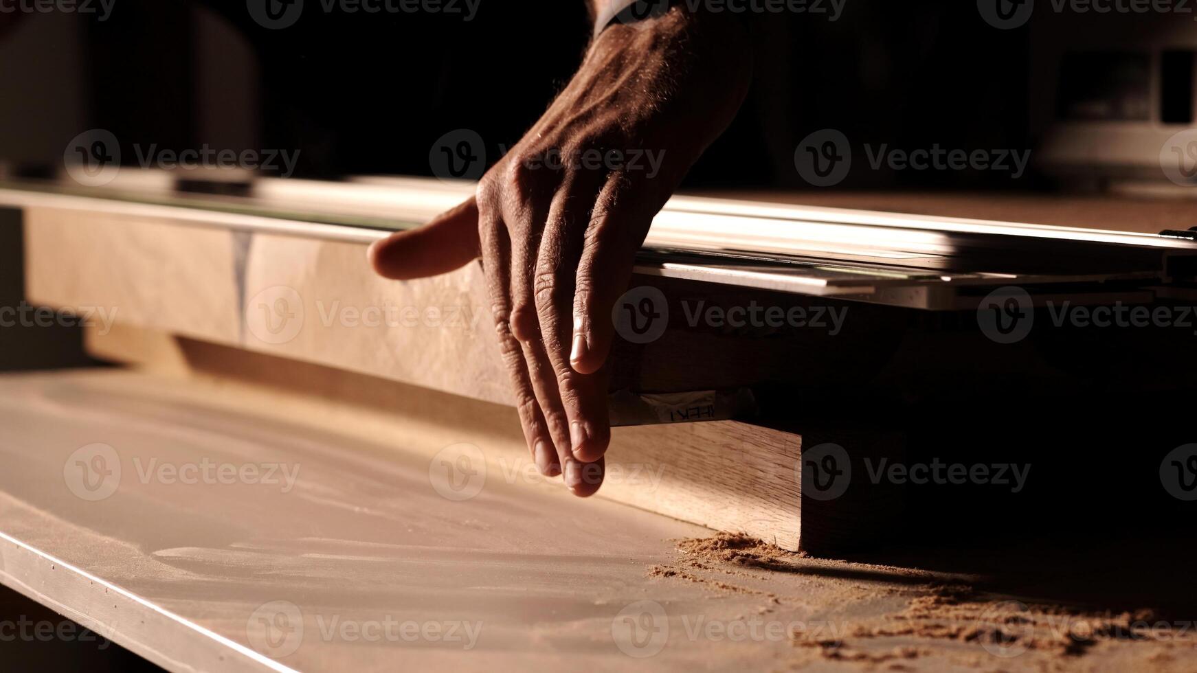 Closeup hand gently glides over the wood, furniture production. man checks the quality of cutting and polishing a wooden surface. Professional carpenter cutting wooden board at sawmill. photo