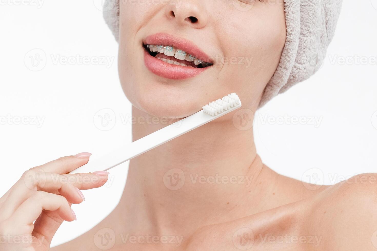 Smiling woman holding toothbrush with braces on teeth isolated on white background, Concept oral hygiene and health care. Orthodontic concept. Invisible braces aligner, recommending this new treatment photo