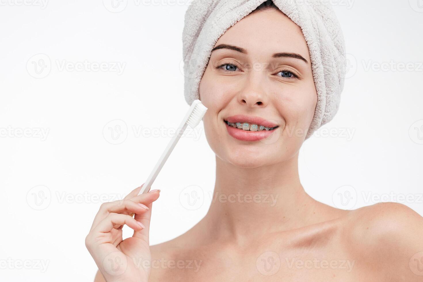 Smiling woman holding toothbrush with braces on teeth isolated on white background, Concept oral hygiene and health care. Orthodontic concept. Invisible braces aligner, recommending this new treatment photo