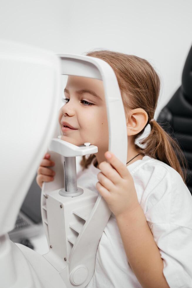 Close-up of a little girl with deep eyes undergoing vision diagnostics using a slit lamp in an ophthalmology clinic. A perfect moment highlighting the importance of caring for children's vision photo