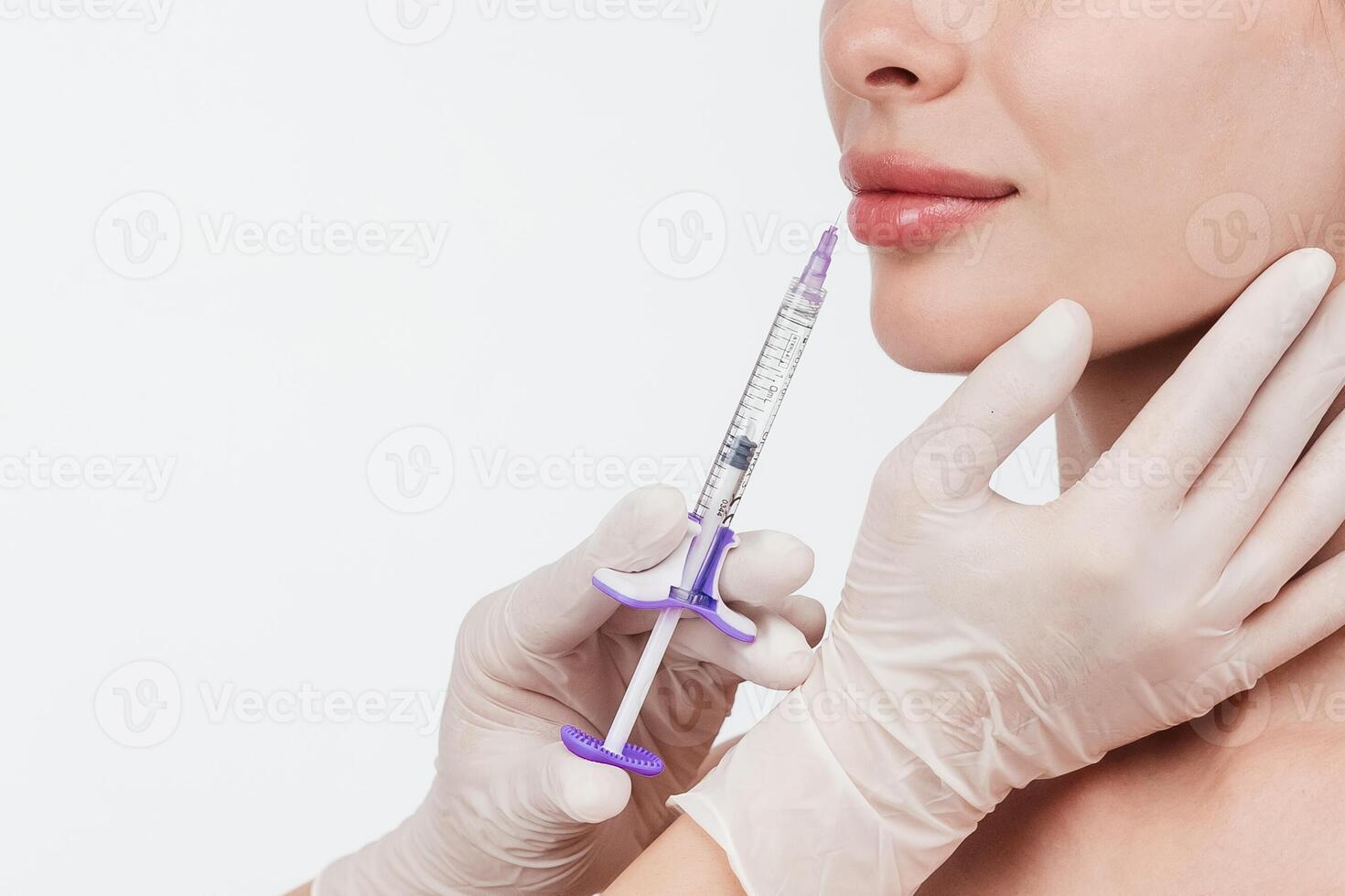 Woman while procedure lip augmentation at cosmetology clinic with beautician. Filler injection for beautiful female lips augmentation with hyaluronic, side view. photo