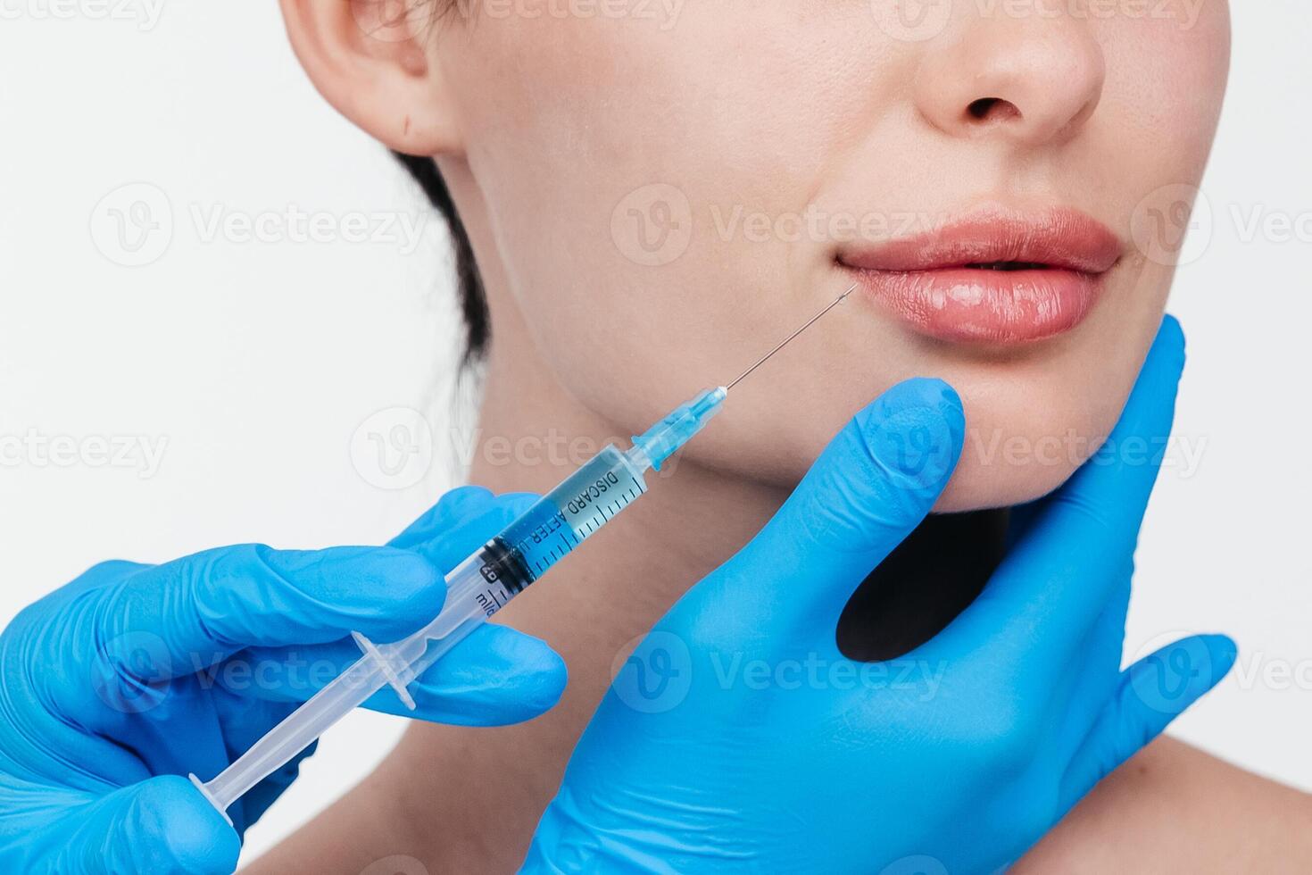 Woman while procedure lip augmentation at cosmetology clinic with beautician. Filler injection for beautiful female lips augmentation with hyaluronic, side view. photo