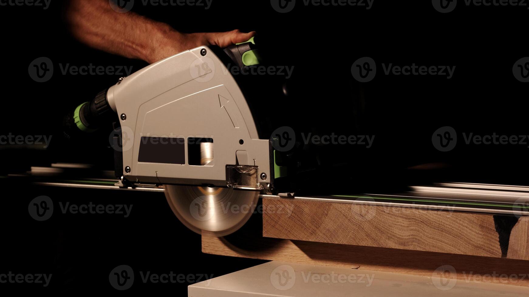 Close-up of a man cuts a wooden plank with an electric circular saw in a workshop. Cutting a piece of wood on a circular saw in backlight. Ideal topics related carpentry, efficient sawing techniques photo