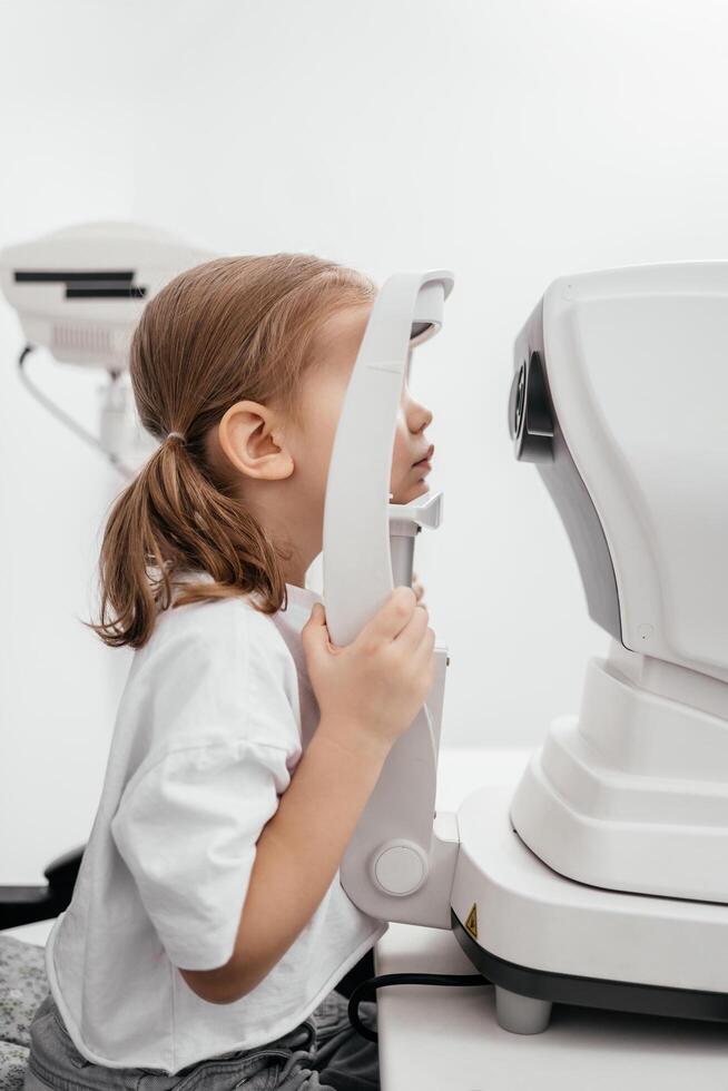 Close-up of a little girl with deep eyes undergoing vision diagnostics using a slit lamp in an ophthalmology clinic. A perfect moment highlighting the importance of caring for children's vision photo