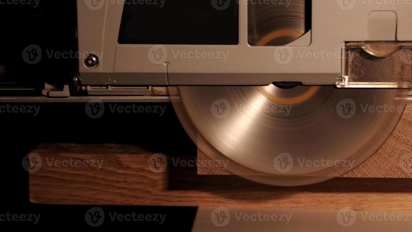 Construction Contractor Cutting To Size Wood Beam Using Portable Circular Saw Close Up. Worker using a circular saw to cut a wood in a factory with selective focus. Industrial Equipment Theme. photo